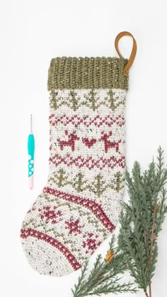 a knitted christmas stocking next to a crochet ornament and needles