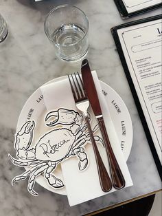 a plate with a crab cut out on it next to a fork and knife sitting on a table