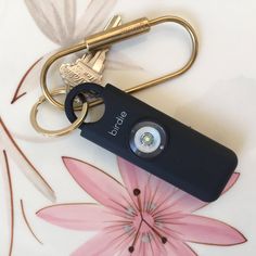 a keychain with a camera attached to it sitting on top of a flower