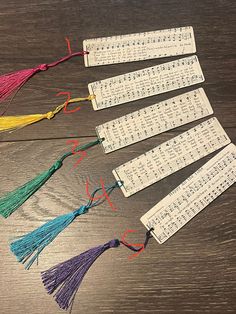 five bookmarks with musical notes and tassels on top of a wooden table