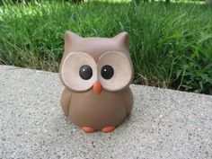 an owl figurine sitting on top of a cement slab in front of some grass