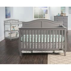 a baby crib in a room with hardwood floors and furniture on the other side