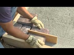 a man laying bricks on the ground with gloves and work gloves around his feet,