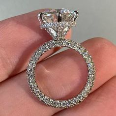 a close up of a person's hand holding a ring with diamonds on it