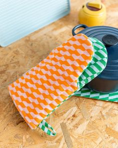 an oven mitt sitting on top of a wooden floor next to a pot holder