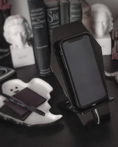 a cell phone is sitting on a stand next to some books and other items in front of it