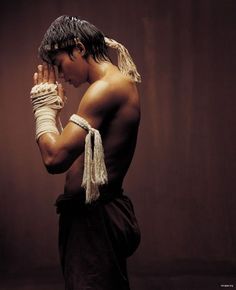 a man with no shirt on holding his hands to his face while standing in front of a brown background