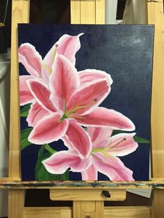 a painting of pink lilies on a easel in front of a black background