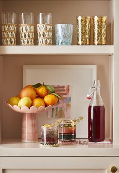 a shelf filled with lots of different types of fruit and glasses on top of it