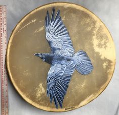 a blue bird on a gold plate next to a measuring tape