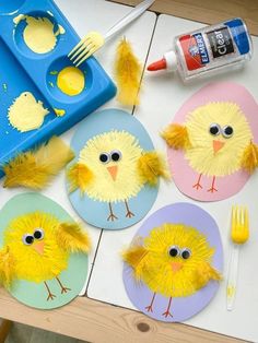 paper plates with yellow chicks on them next to paintbrushes and plastic spoons