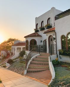 the sun is setting behind a house with steps leading up to it's front door