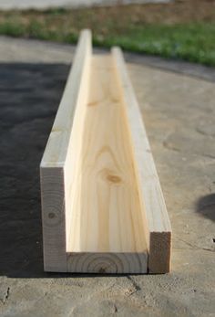 a wooden bench sitting on top of a cement floor next to a green grass covered park