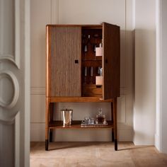 a wooden cabinet sitting on top of a hard wood floor next to a white wall