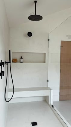 a bathroom with a shower head, shelf and tiled floor