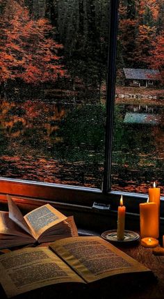 an open book sitting on top of a table next to candles