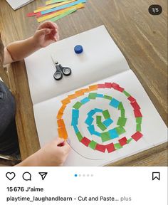 a child is making a paper craft with colored strips and scissors on top of a table