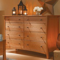 a wooden dresser sitting in a bedroom next to a chair and lamp on top of it