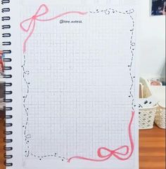 an open notebook with pink crayons on it and a red ribbon in the middle