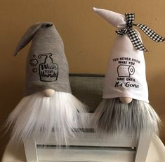 two gnomes sitting on top of a window sill wearing hats with sayings