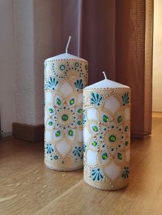 two white candles sitting on top of a wooden table