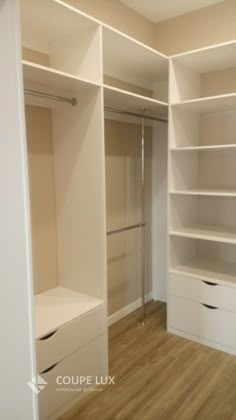 an empty walk in closet with white shelving and drawers on each side, next to a wooden floor