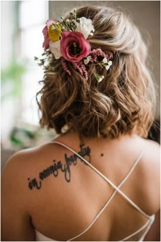 the back of a woman's head with flowers in her hair and writing on it