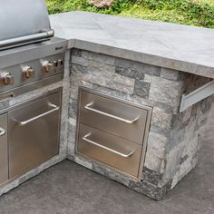 an outdoor kitchen with stainless steel appliances and stone counter tops, along with grass in the background