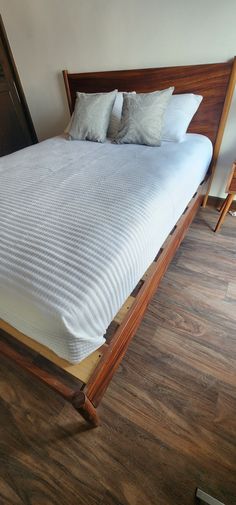 a bed with two pillows on top of it and wooden frame around the headboard