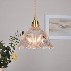 a glass light hanging from a ceiling in a room with flowers on the table next to it