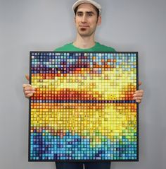 a man is holding up a large piece of art made out of legos and colored blocks