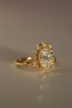 a gold ring with a pear shaped diamond surrounded by small white diamonds on the side