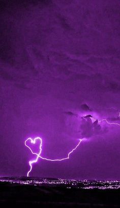 purple lightning strikes in the sky over a city