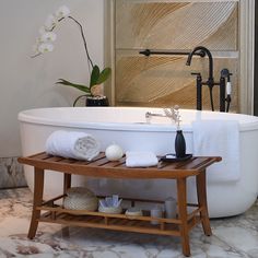 a white bath tub sitting next to a wooden shelf