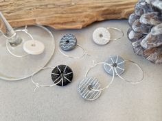 four different types of earrings sitting on top of a table next to a pine cone