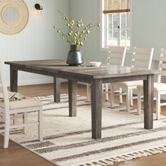 a dining room table with chairs and a rug on the floor