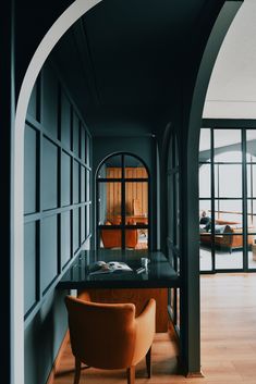 an archway leading into a room with a desk and chair in it, next to a large window