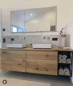 a bathroom with two sinks, mirrors and towels on the counter top in front of it