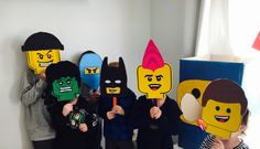 some kids are holding up paper masks with legos on them and one is wearing a batman mask