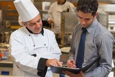 two chefs are looking at something on a tablet