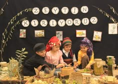 three children sitting at a table with baskets and food