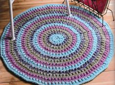 a crocheted rug is on the floor next to a chair