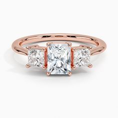 an engagement ring with three princess cut diamonds in rose gold and white topazte