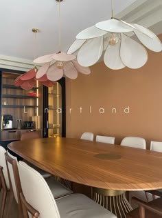 a large wooden table with white chairs around it and a chandelier hanging from the ceiling