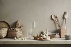 an assortment of kitchen utensils on a table with a basket and spoons