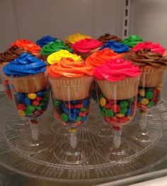 there are cupcakes with candy in them on the glass plate, ready to be eaten