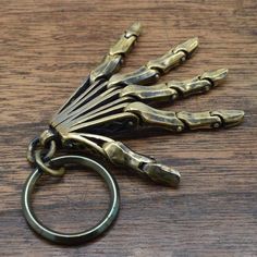 an antique brass skeleton hand keychain on a wooden table with a metal ring