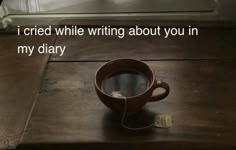 a coffee cup sitting on top of a wooden table next to a mirror with the words i tried while writing about you in my diary