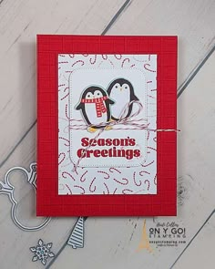 a card with two penguins on it and the words season's greetings written in red