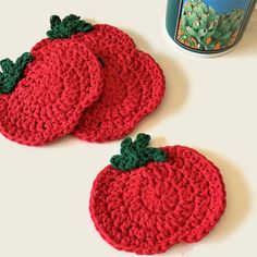 two crocheted coasters sitting on top of a table next to a can